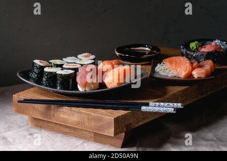 Sushi Set nigiri Sushi Rollen auf japanischer Holz-, das Board mit Sojasauce, Essstäbchen auf grau Leinen Tischdecke. Japan Menü Stockfoto