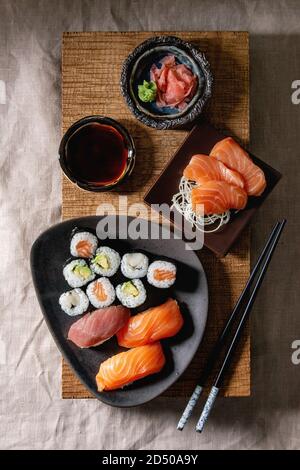 Sushi Set nigiri Sushi Rollen in keramischen Platten auf japanischer Holz-, das Board mit Sojasauce und Stäbchen über graues Leinen Tischdecke backgrou Stockfoto