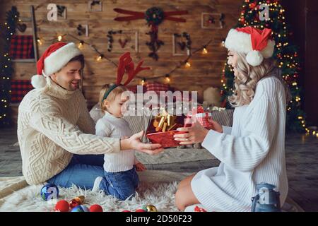 Eltern schenken dem Kind im Zimmer Geschenke Weihnachten Stockfoto