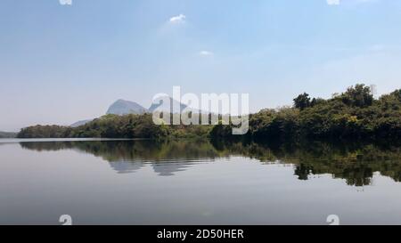 Ein Panoramablick auf den umliegenden Wald und ferne Berge von einem Boot auf dem Fluss periyar im südlichen indischen Bundesstaat Kerala. Stockfoto