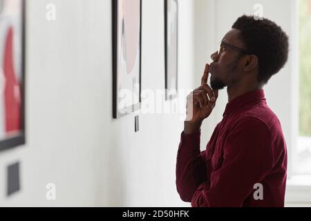 Seitenansicht Porträt eines jungen afroamerikanischen Mannes, der Gemälde ansieht und in einer Kunstgalerie oder Museumsausstellung denkt, Kopierraum Stockfoto