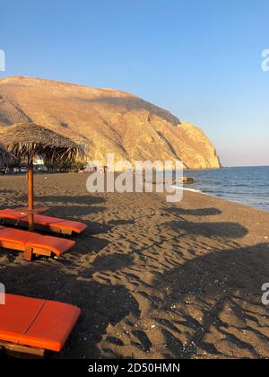 Schöner schwarzer Sandstrand von Perissa, auf der Insel Santorini in Griechenland, bei Sonnenuntergang. Stockfoto