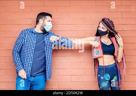 Glückliche Freunde tragen schützende Gesichtsmaske beim Gruß durch stoßen Ihre Ellbogen Stockfoto