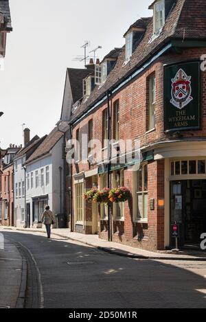 Sehen Sie im Sommer eine Frau, die allein entlang der historischen Kingsgate Street in Winchester, Hampshire, England, Großbritannien, geht Stockfoto