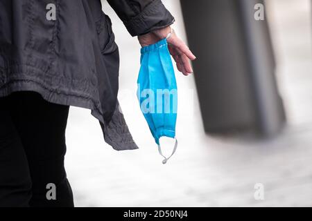 Delmenhorst, Deutschland. Oktober 2020. Eine Frau geht mit einer Mund-Nase-Schutzmaske in der Hand durch die Fußgängerzone von Delmenhorst. Kredit: Mohssen Assanimoghaddam/dpa/Alamy Live Nachrichten Stockfoto