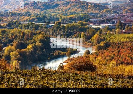 Blick von oben auf den Fluss Tanaro unter bunten Herbstbäumen in der Nähe der Stadt Alba im Piemont, Norditalien. Stockfoto