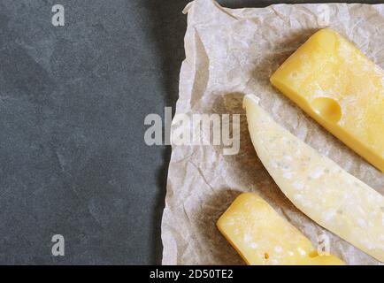 Schimmel auf Käse. Hartkäse mit weißem und schwarzem Schimmel auf dem Papier. Schimmelpilz auf der Nahrung. Flauschige Sporen Schimmel . Stockfoto