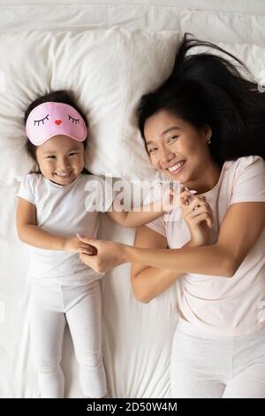 Blick von oben lächelnde asiatische Mutter und Tochter entspannen im Bett Stockfoto