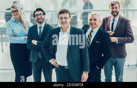 Selbstbewusster Geschäftsmann und seine Kollegen stehen im Büro. Stockfoto