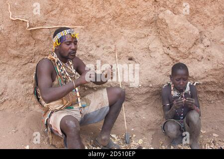 Hadza Männer Vorbereitung der Pfeile vor einer Jagd Expedition. Die Hadza, oder Hadzabe, sind eine kleine ethnische Gruppe in Nord-Zentral-tansania, leben um L Stockfoto