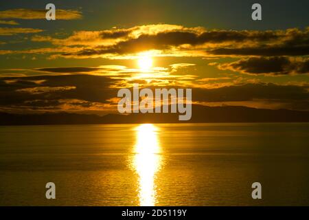 Sonnenuntergang über dem Meerwasser mit der Alaskan Küste in Silhouette Stockfoto