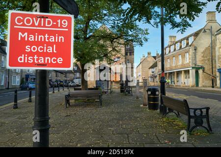 „Covid-19 Pflegen Sie soziale Distanz“ auf einer Post am Marktplatz in Oundle, England. Oktober 2020. Stockfoto