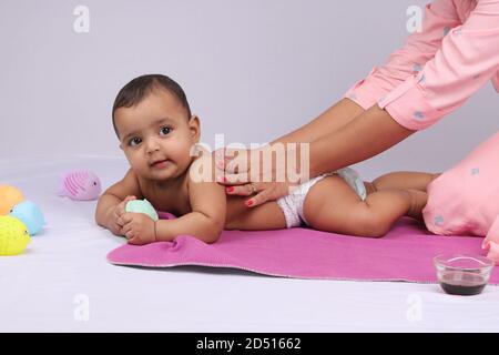 Indische Mutter massiert ihr schönes Baby. Stockfoto