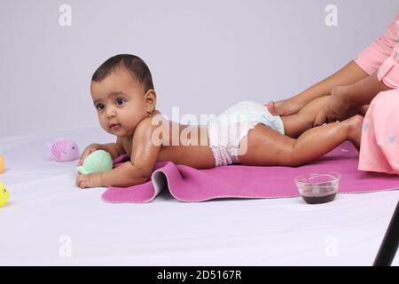 Indische Mutter massiert ihr schönes Baby. Stockfoto