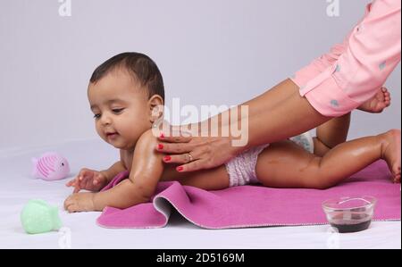 Indische Mutter massiert ihr schönes Baby. Stockfoto