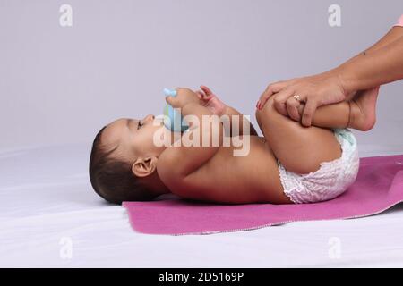 Indische Mutter massiert ihr schönes Baby. Stockfoto