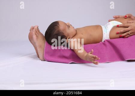 Indische Mutter massiert ihr schönes Baby. Stockfoto