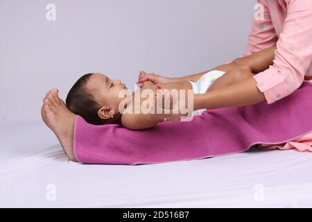 Indische Mutter massiert ihr schönes Baby. Stockfoto