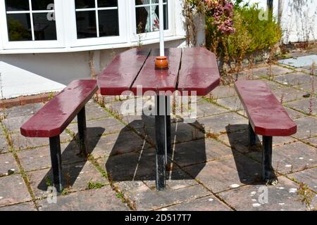 Nahaufnahme von rot lackiertem leerem Tisch und Bank bei Restaurant im Freien ohne Leute in der Sommersonne Stockfoto