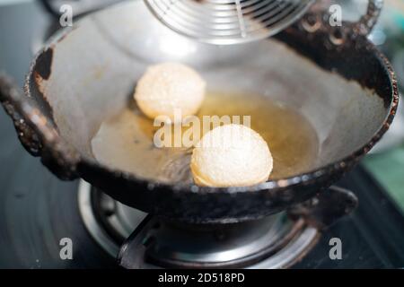 Schuss von nordindischen Street Food Snack gol gappe Pani puri oder Puchke, die aus dem Teig in heißem Öl gebraten werden Um sie rund hohlen goldenen Kugel Kugeln zu machen Stockfoto