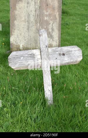 Schließen des rustikalen Holzkreuzes im Kirchhof mit Gras gegen Kopfstein im Sommer Stockfoto