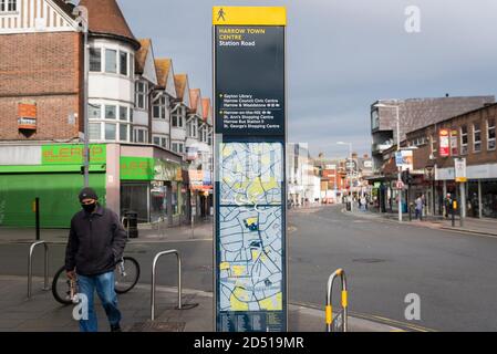 London, Großbritannien. 12. Oktober 2020. Ein Mann mit Gesichtsmask läuft an einem Stadtplan im Stadtzentrum von Harrow vorbei. Es wird berichtet, dass fünf Londoner Stadtbezirke mehr als 100 neue COVID-19 Fälle pro 100,000 Einwohner in der Woche bis zum 8. Oktober hatten - Richmond, Hackney, Ealing, Redbridge und Harrow. Während Großbritannien landesweit einen Anstieg der COVID-19-Fälle erlebt, kündigt Premierminister Boris Johnson im Unterhaus ein neues dreistufiges lokales Sperrsystem an, um die Ausbreitung des Virus zu bekämpfen. Kredit: Stephen Chung / Alamy Live Nachrichten Stockfoto