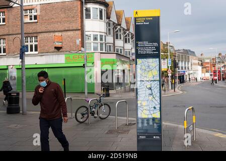 London, Großbritannien. 12. Oktober 2020. Ein Mann mit Gesichtsmask läuft an einem Stadtplan im Stadtzentrum von Harrow vorbei. Es wird berichtet, dass fünf Londoner Stadtbezirke mehr als 100 neue COVID-19 Fälle pro 100,000 Einwohner in der Woche bis zum 8. Oktober hatten - Richmond, Hackney, Ealing, Redbridge und Harrow. Während Großbritannien landesweit einen Anstieg der COVID-19-Fälle erlebt, kündigt Premierminister Boris Johnson im Unterhaus ein neues dreistufiges lokales Sperrsystem an, um die Ausbreitung des Virus zu bekämpfen. Kredit: Stephen Chung / Alamy Live Nachrichten Stockfoto