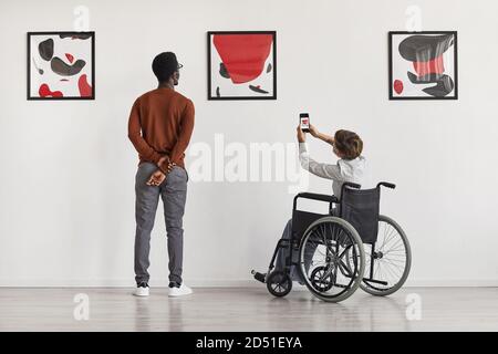 Rückansicht Porträt der jungen Frau mit Rollstuhl Foto von Kunstwerken beim Besuch zugänglich Museum, Kopierraum Stockfoto