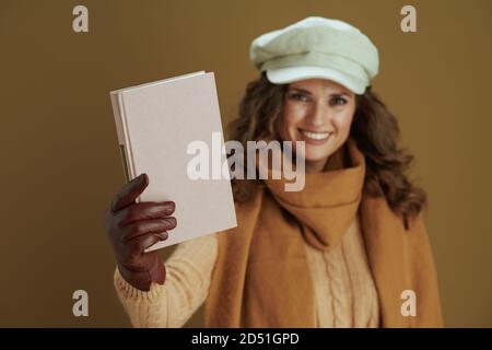 Hallo Herbst. Glückliche moderne 40 Jahre alte Frau im Schal mit Buch und Lederhandschuhe auf beigem Hintergrund. Stockfoto