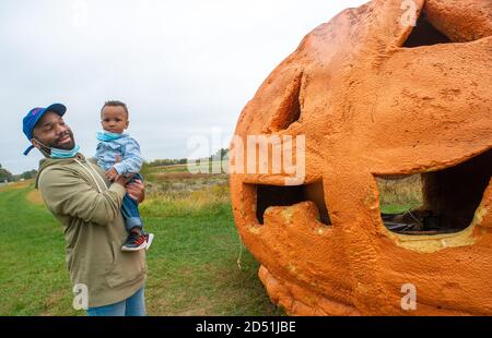 Ivyland, Usa. Oktober 2020. Von links sehen Ian Kimble und Zioan Kimble, 2, aus Philadelphia den überdimensionalen Kürbis, während sie Kürbisse pflücken Sonntag, 11. Oktober 2020 auf der Solly Brothers Farm in Ivyland, Pennsylvania. Kredit: William Thomas Cain/Alamy Live Nachrichten Stockfoto