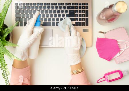 Obere Ansicht der weiblichen Hände in weißen Gummihandschuhen Desinfektion Laptop mit Desinfektionsmittel und Reinigungstuch in der Nähe von medizinischen Maske, ein antibakterielles Mittel und Stockfoto