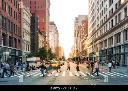 Menschenmassen, die an der Kreuzung von 23rd Street und Fifth Avenue in Midtown Manhattan, New York City NYC, durch einen geschäftigen Fußgängerüberweg laufen Stockfoto