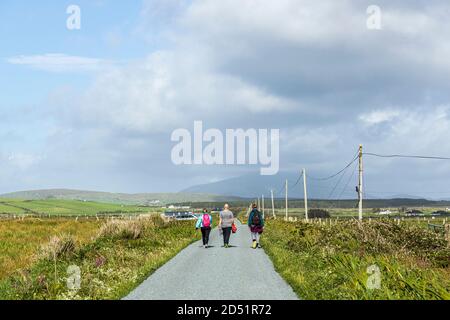 Wanderer auf einer einspurigen Straße entlang der Killeen-Schleife Spaziergänge in der Nähe von Louisburgh, County Mayo, Irland Stockfoto