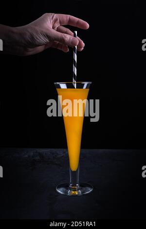 Frau Hand Putting Papier Stroh in hohes Glas mit Kürbis alkoholfreien Mocktail stehen auf schwarz strukturierten Stein Tischfläche. Halloween kein Plastik Stockfoto