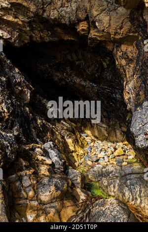 Mehrfarbige Steine in einer kleinen Höhle am Strand von Louisburgh, County Mayo, Irland Stockfoto