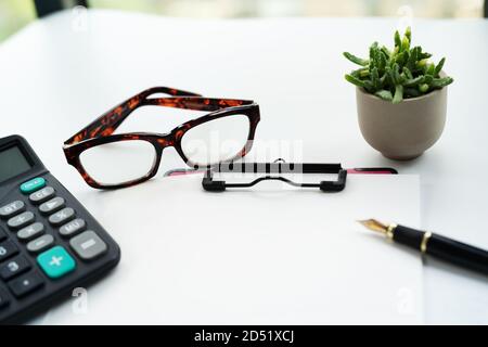 Geschäftsobjekte, Zwischenablage mit leerem Blatt Papier, Stift, Brille und Taschenrechner auf weißem Hintergrund Stockfoto