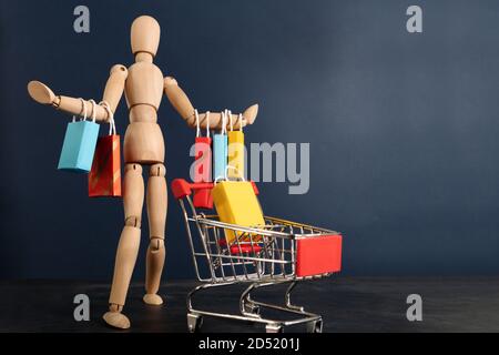 Fröhliches happy shopaholic Puppe mit vielen Einkaufstüten auf Arm und Warenkorb Stockfoto