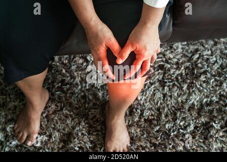 Alte Frau mit Knieschmerzen zu Hause, Gesundheit Problem Konzept Stockfoto