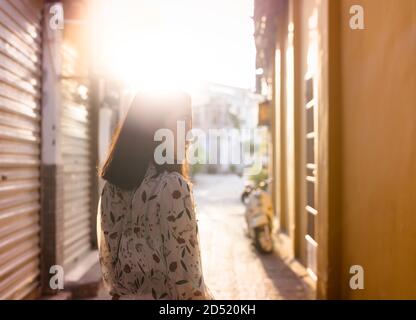 Frau auf dem Gehweg in der Enge des Dorfes Städtische Landschaft am Sonnenuntergang, auf der Seite Stockfoto