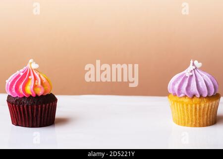 Süße Kuchen Dessert mit kleinen Herzen auf lila und Rainbow Creme auf rosa Hintergrund Stockfoto