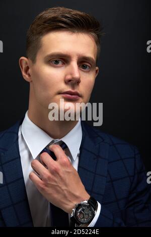 kaukasischen Business-Mann begradigen eine Krawatte isoliert über schwarzem Hintergrund. Junger Mann in formellen Anzug Vorbereitung für die Sitzung Stockfoto