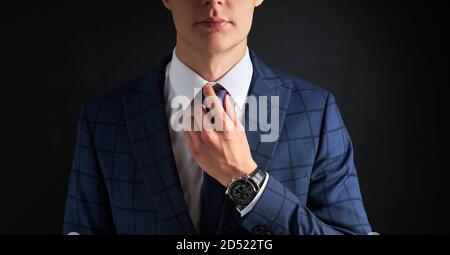 Cropped Business Mann gerade eine Krawatte isoliert über schwarzem Hintergrund. Junge Kerl in formellen Anzug Vorbereitung für die Sitzung Stockfoto