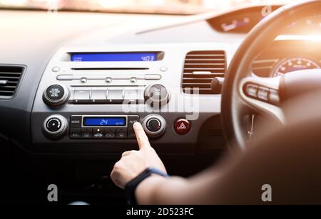 Frau drücken Sie die Klimaanlage im Auto an Stockfoto