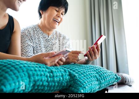 Erwachsene Frau und Tochter mit Smartphone. Frau lächelt Blick auf Handy-Display Stockfoto