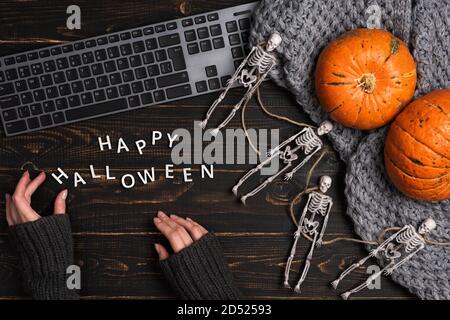 Weibliche Hände und Halloween Dekorationen mit Skelett und Laptop Stockfoto
