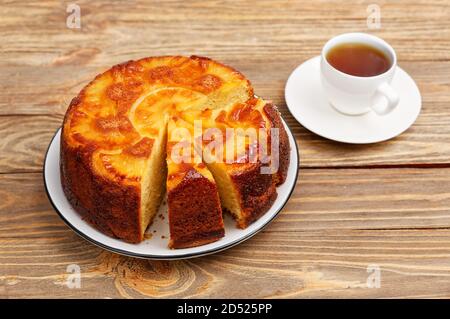 Ananas Upside Down Kuchen und Tasse Tee auf Holztisch. Geringer Fokus. Stockfoto