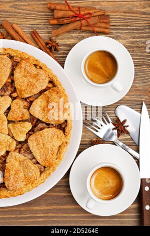 Nahaufnahme hausgemachter Apfelkuchen mit Zimt und zwei weißen Tassen Kaffee Espresso auf Holztisch. Draufsicht. Stockfoto