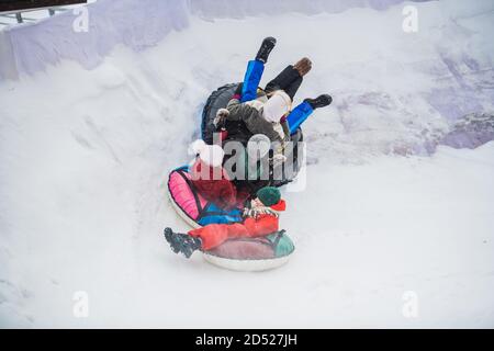 Die Eltern kauften ihre Kinder Tubing und nun fährt die ganze Familie die Eisrutsche hinunter. Stockfoto