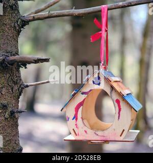 Ein Holzdosierer mit Flecken von mehrfarbiger Farbe hängt an Ein Baum im Park Stockfoto