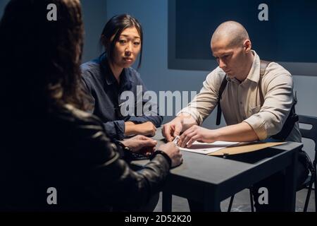 Der Ermittler führt ein Verhör durch, zeigt die verdächtigen Fotos von Komplizen. Stockfoto